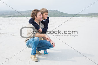 Side view of a casual man and son relaxing at beach