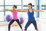 Two sporty women stretching hands at yoga class