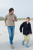 Young man and son jogging at beach