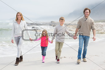 Happy family of four walking hand in hand at beach