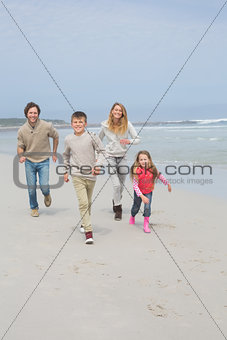 Happy family of four running at beach