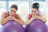 Two fit women with exercise balls at gym