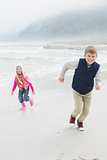 Full length of happy siblings running at beach