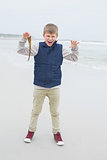 Full length of a cheerful boy holding dry leaf at beach