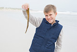 Smiling young boy holding a dry leaf at beach