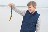 Boy looking at a dry leaf at beach