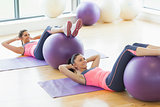 Two young women exercising with fitness balls at gym