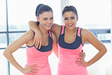Two fit young women smiling in a bright exercise room