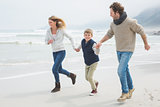 Happy family of three running at beach