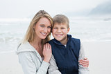 Cute boy with smiling mother at beach
