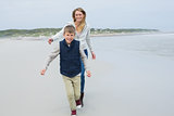 Smiling woman and boy running at beach