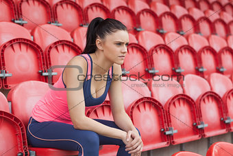 Serious toned young woman sitting on chair in the stadium