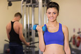 Sporty woman with dumbbell and man using lat machine in the gym