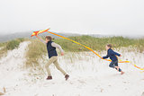 Cheerful kids running with kite at beach