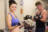 Young woman and man with dumbbells in gym