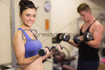 Young woman and man with dumbbells in gym