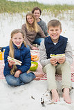 Happy family of four at a beach picnic