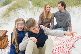 Happy family of four at a beach picnic