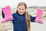 Cute smiling girl holding her wellington boots at beach