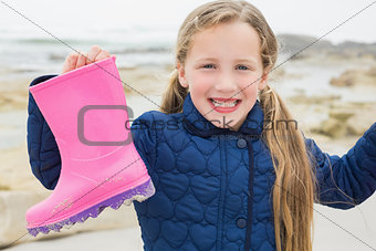 Cute girl holding her wellington boot at beach