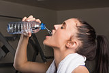 Close-up of a young woman drinking water in gym