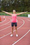 Toned woman doing stretching exercise on the running track