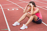 Young sporty woman sitting on the running track