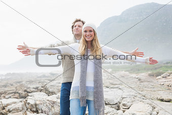 Casual couple stretching hands out on rocky landscape
