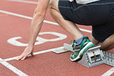 Mid section of a man ready to race on running track