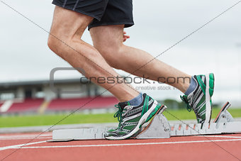 Low section of a man ready to race on running track