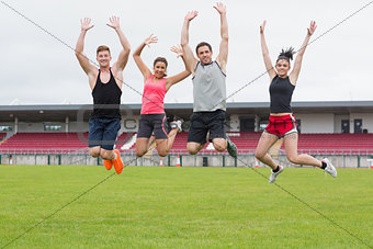 Fit people jumping on ground against the stadium