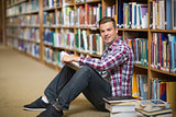Happy student sitting on library floor reading