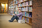 Smiling student sitting on library floor reading