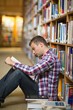 Focused student sitting on library floor reading