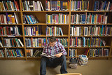 Concentrating young student sitting on library floor reading
