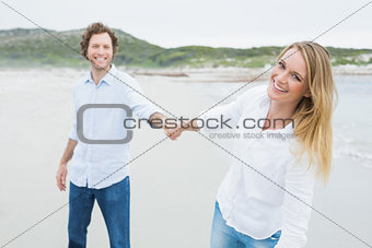 Smiling casual couple holding hands at beach