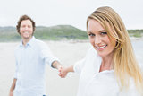 Smiling casual couple holding hands at beach