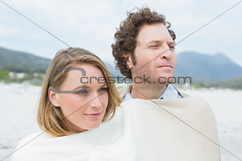 Couple wrapped in blanket at beach