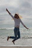 Casual young woman jumping at beach