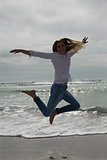 Full length of casual woman jumping at beach