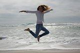 Full length of a casual woman jumping at beach