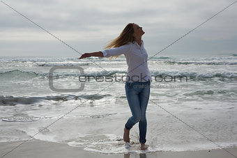 Woman with eyes closed and arms outstretched at beach