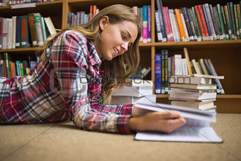 Smiling student lying on library floor reading