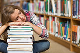 Sleeping student sitting on library floor leaning on pile of books