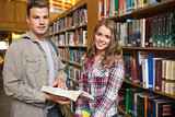 Happy classmates standing in library looking at camera