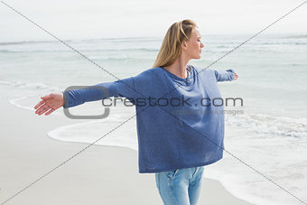 Woman with eyes closed and arms outstretched at beach