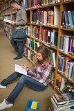 Concentrating student reading book on library floor