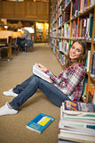 Cheerful student reading book on library floor