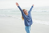 Happy woman standing with hands raised at beach
