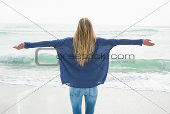 Rear view of a blond with arms outstretched at beach
